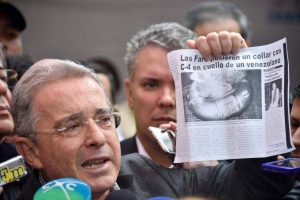 Алваро Урибе в разгара на кампанията–размахва вестник със снимка на отвлечен от партизани заложник с "яка" от експлозив около врата му