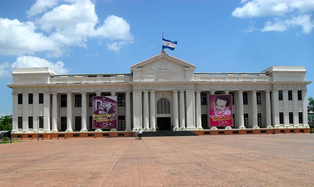 Националният дворец в Манагуа, който по времето на Сомоса е бил парламент, днес е Национален дворец на културата и е украсен с постери в чест на националните герои Аугусто Сесар Сандино и Карлос Фонсека Амадор, основател на Сандинисткия фронт за национално освобождение (FSLN). Снимка: nuevodiario.com.ni