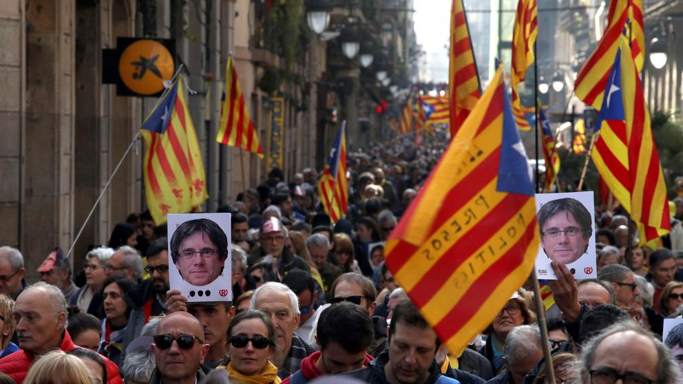 Участници в масовата демонстрация в Барселона срещу отлагането на парламентарната сесия за издигане на премиерската кандидатура на Карлес Пучдемон носят негови портрети. Снимка: La Vanguardia