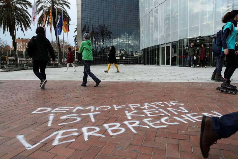"Демокрацията не е престъпление" е написано на немски върху тротоара пред германското консулство в Барселона. Снимка: EFE