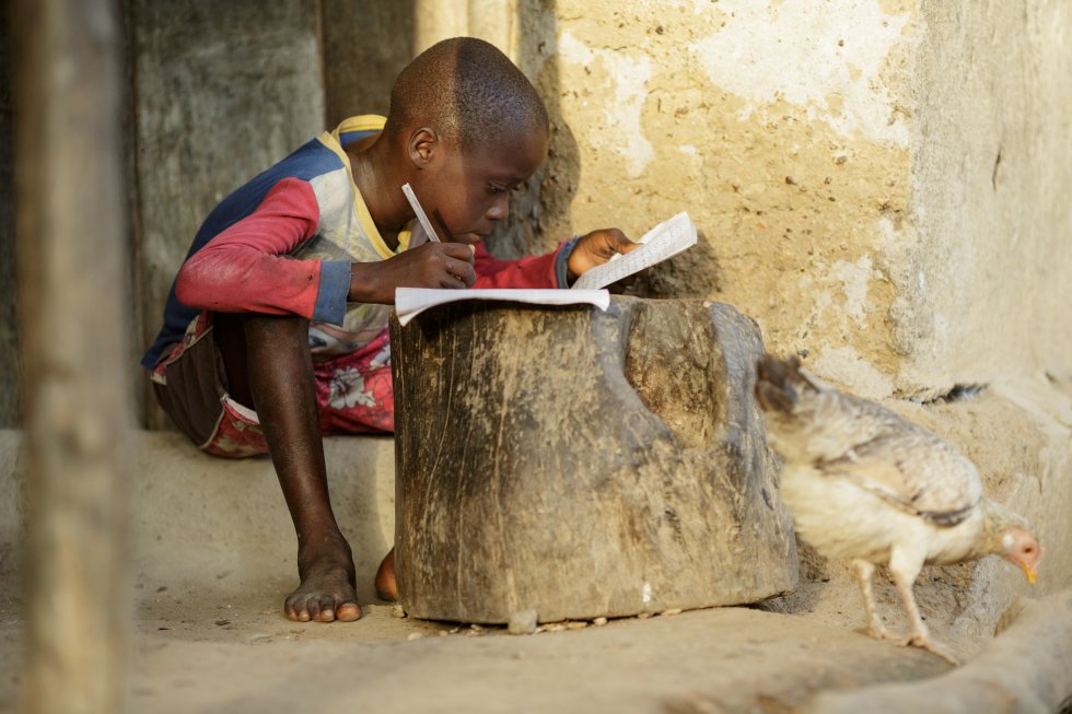 Дете от Сиера Леоне пише домашните си на дръвник пред дома си в село Матене. Снимка: УНИЦЕФ