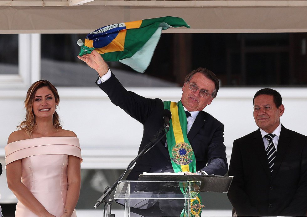 Жаир Болсонаро размаха пред множеството на Площада на трите власти в град Бразилия националното знаме и провъзгласи, че никога няма да позволи то да стане червено, освен ако не бъде обагрено от кръв в защита на страната. До него бе жена му Мишел Болсонаро и вицето му–бившият генерал Амилтон Моурао . Снимка: EFE
