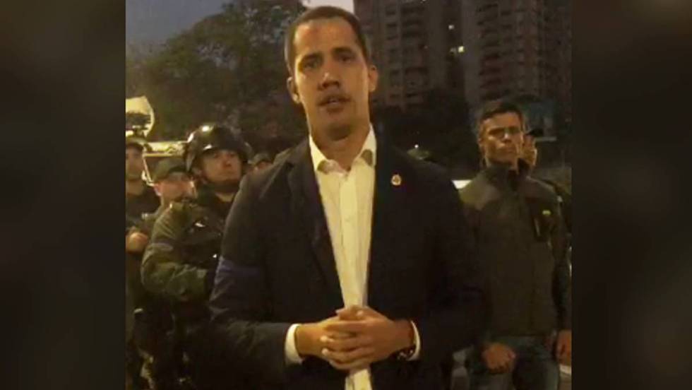 Хуан Гуайдо в кадър от видеозаписа, в който зове за преврат. Зад него вдясно е Леополдо Лопес. Отляво се виждат демонстративно подредени военни. Снимка: El Pais