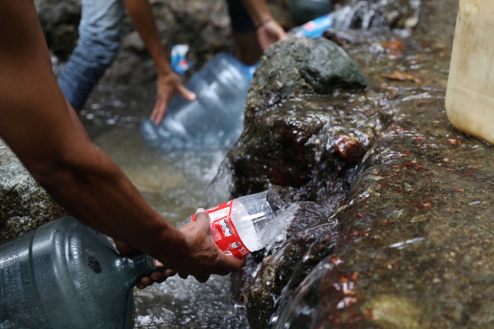 Хора наливат вода от поточе на планината Уарайра Репано. Снимка: EFE