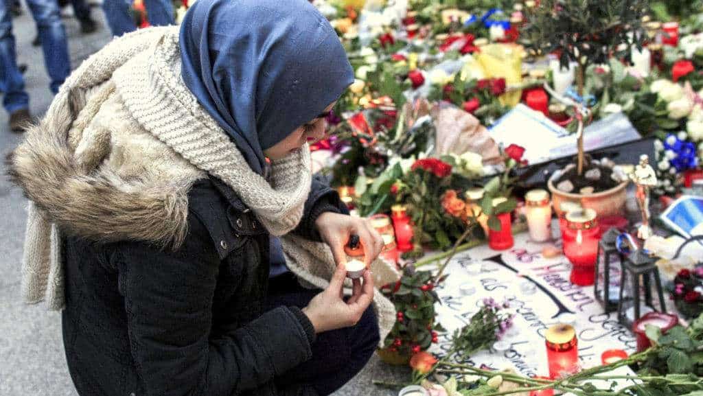 BERLIN, GERMANY - NOVEMBER 16:  A young Muslim woman lights a candle outside the French Embassy among candles, messages and flowers left by mourners commemorating the victims of last Friday's terrorist attacks in Paris that have left over 130 people dead on November 16, 2015 in Berlin, Germany. Eight Muslim organizations in Germany issued a common statement earlier in the day condemning the Paris attacks and citing Islam as a non-violent religion. The Islamic State (IS) claimed responsibility for the attacks and has vowed to launch more.  (Photo by Carsten Koall/Getty Images)