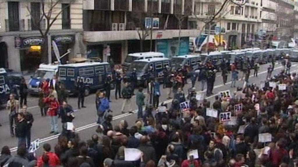 Демонстранти размахват плакати с надписи "Мир" на протест пред обградената от полиция централа на Народната партия в Мадрид след атентата от 11 март 2004 г. Снимка: rtve.es