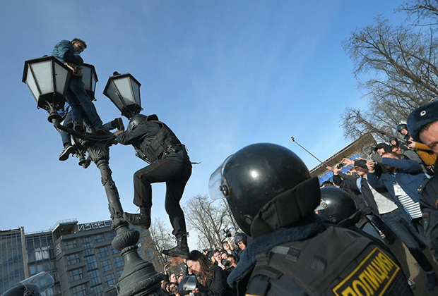 Полицай се катери по улична лампа, за да свали качилите се на нея младежи на площад "Пушкин" в Москва. Снимка: Коммерсантъ