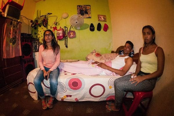 Хосе Рафаел Ногера е на легло у дома си, докато се възстановява от травмите. Край него са жена му и сестра му. Снимка: albaciudad 
