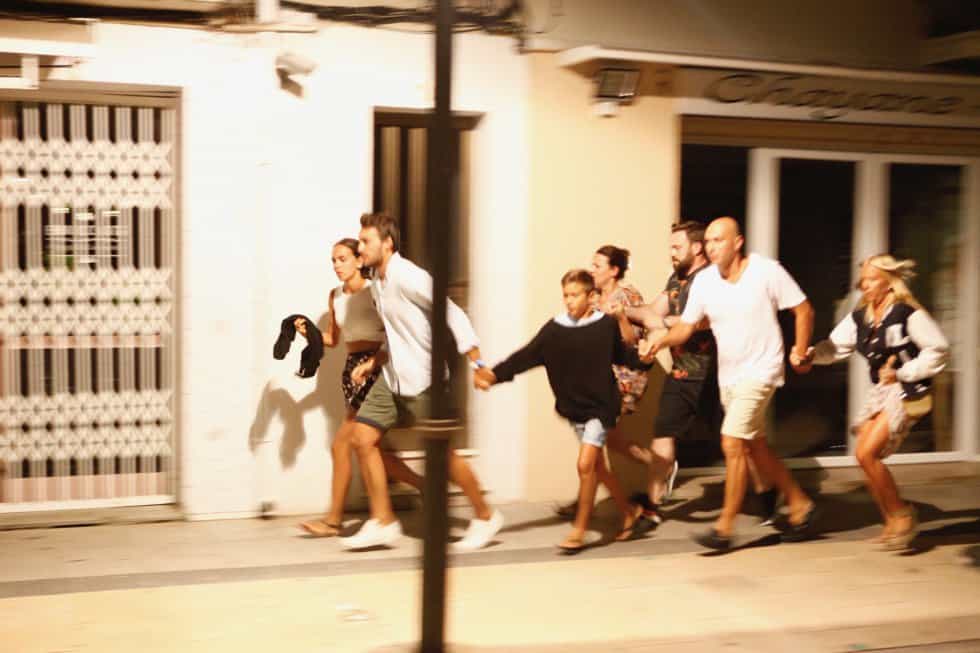Ужасени туристи бягат по улица в Камбрилс, изпълнявайки искането на полицията да се укрият. Снимка: El Pais