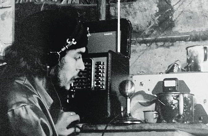 Че Гевара води предаване по "Радио Ребелде" от импровизираното студио в барака в планината Сиера Маестра по време на партизанската война в Куба. 