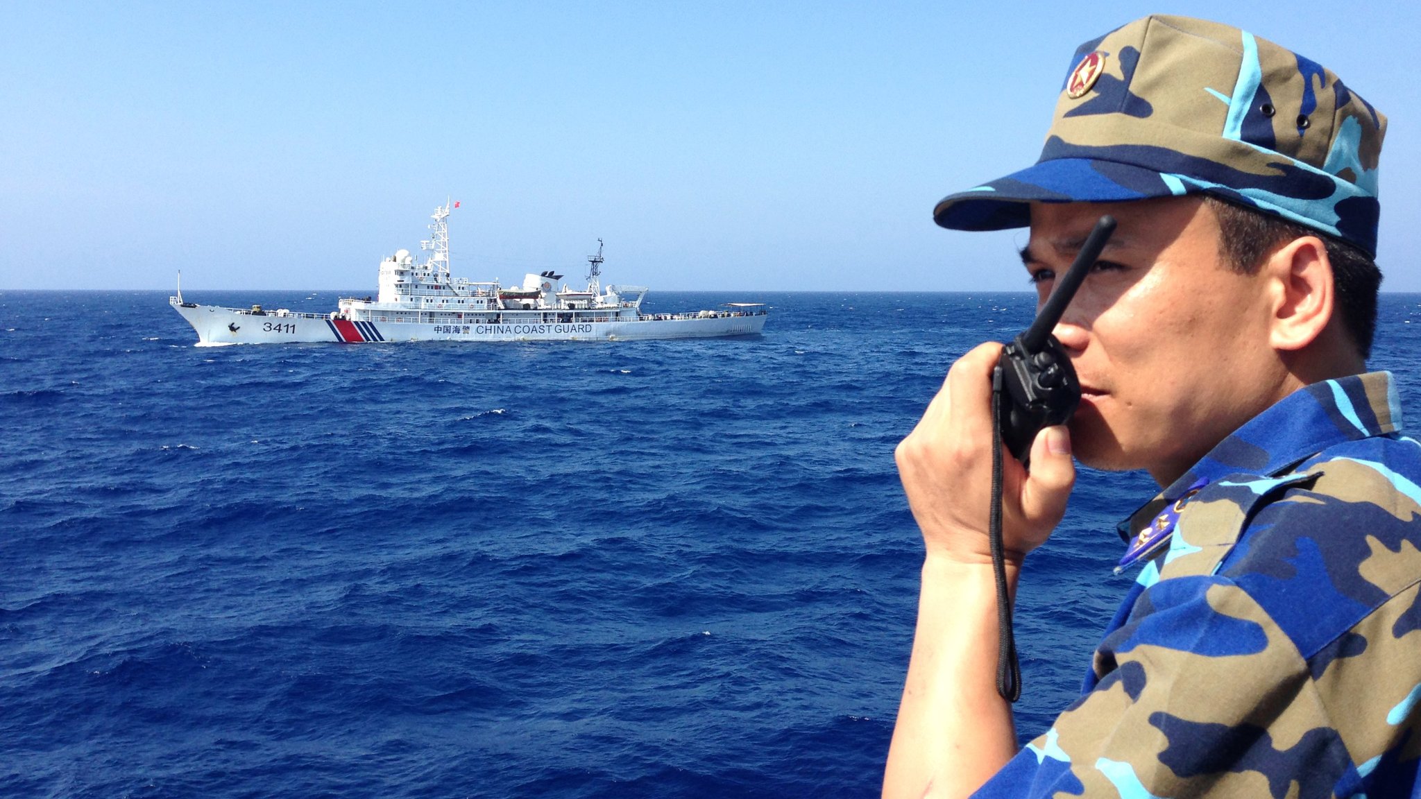 Капитан на виетнамски патрулен кораб докладва на командването си, докато отсреща обикаля и китайски патрулен кораб