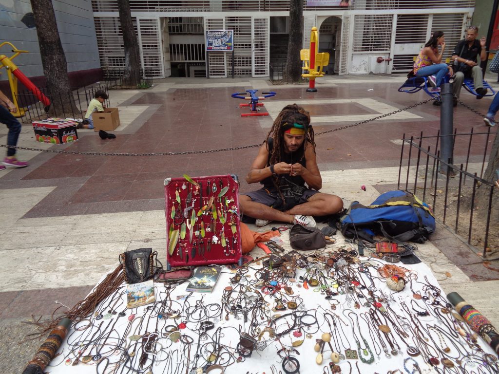 Този младеж продължава да плете гривнички, докато продава изработени от самия него украшения от еко-материали на улица в "Либертадор". Снимка: Къдринка Къдринова