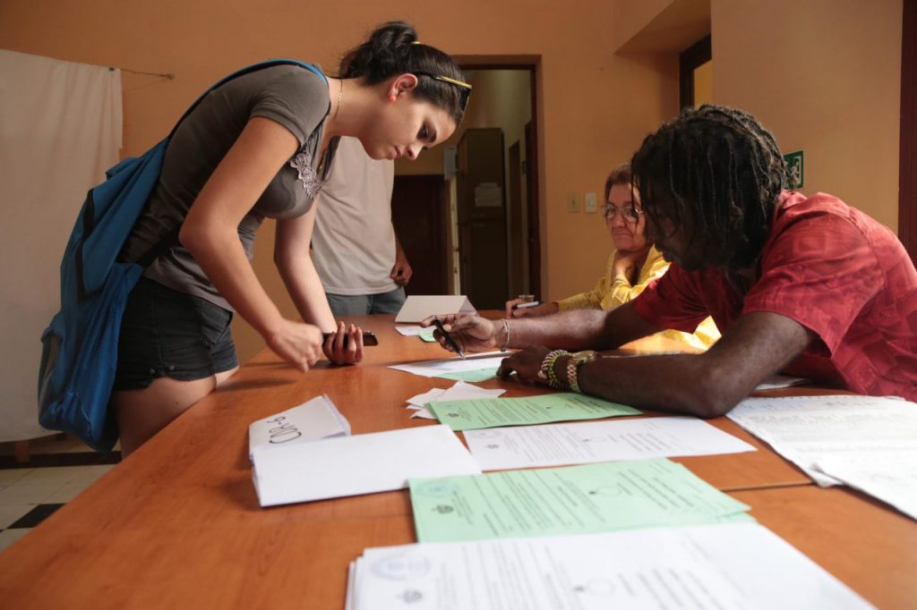Млада кубинска гласоподавателка се отбелязва в изборните списъци преди да даде вота си. Снимка: Resumen Latinoamericano