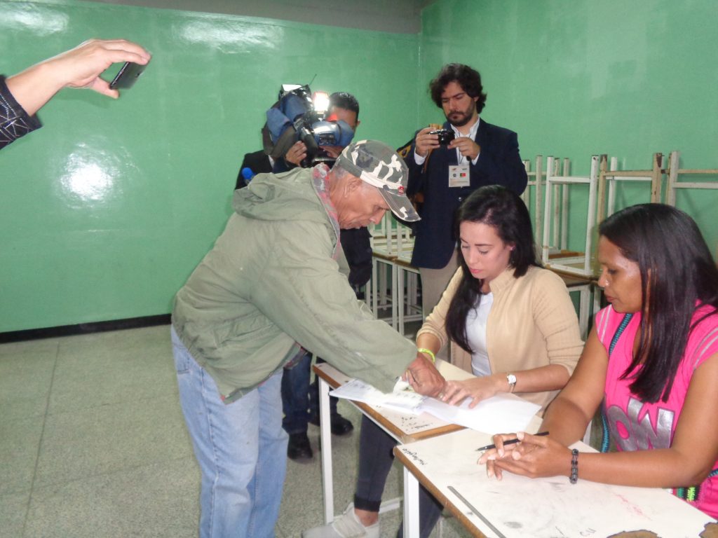 Евродепутатът Жоао Пимента (с фотоапарата в дъното) снима как избирател дава пръстов отпечатък, след като вече е гласувал. Снимка: Къдринка Къдринова