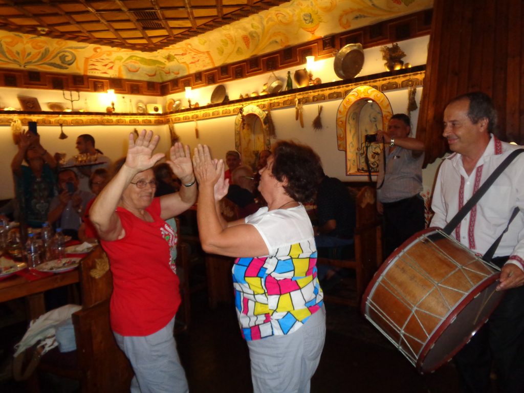Българката Теодора Пиперкова (с червената блуза), която преди 46 г. е последвала мъжа си в Коста Рика, танцува ръценица заедно със сестра си в механата, в която латиногрупата бе посрещната с българска народна музика. Снимка: Къдринка Къдринова
