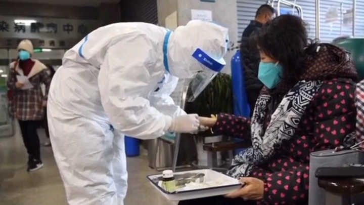 Здравен работник в защитно облекло взима изследвания от пациентка в Ухан с подозрения за заразяване с коронавирус. Снимка: Clarin