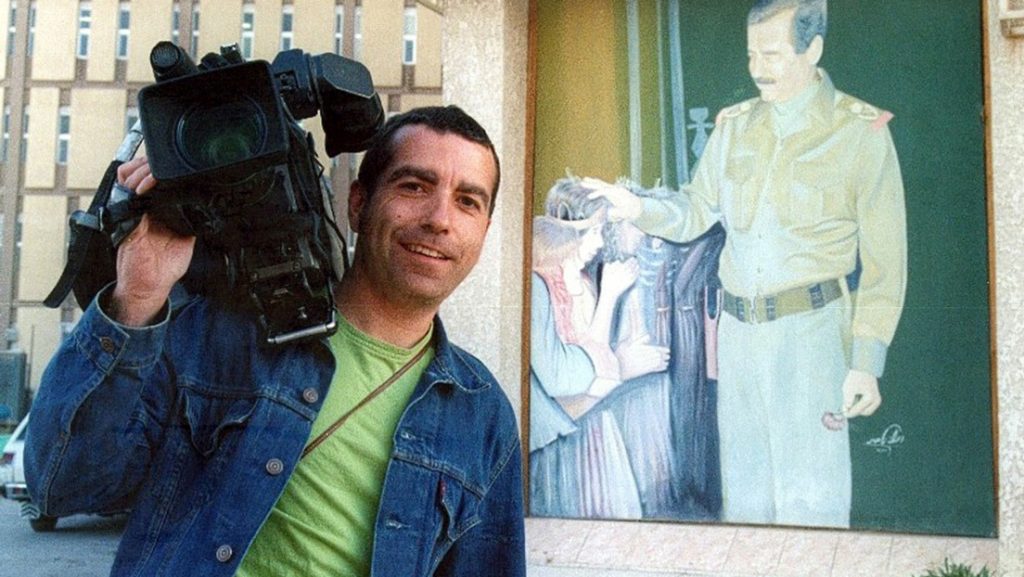 Испанският телевизионен оператор Хосе Коусо с камерата си край портрет на Саддам в Багдад, броени дни преди да бъд убит от американски обстрел по хотел "Палестина". Снимка: Туитър