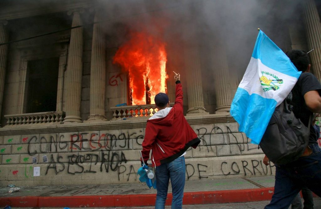 Млад демонстрант изразява гнева си пред вече подпаления от маскирани Конгрес в столицата на Гватемала. Снимка: EFE