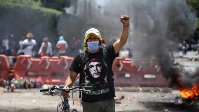 Демонстрант на преградена от барикада улица в колумбийския град Кали. Снимка: EFE