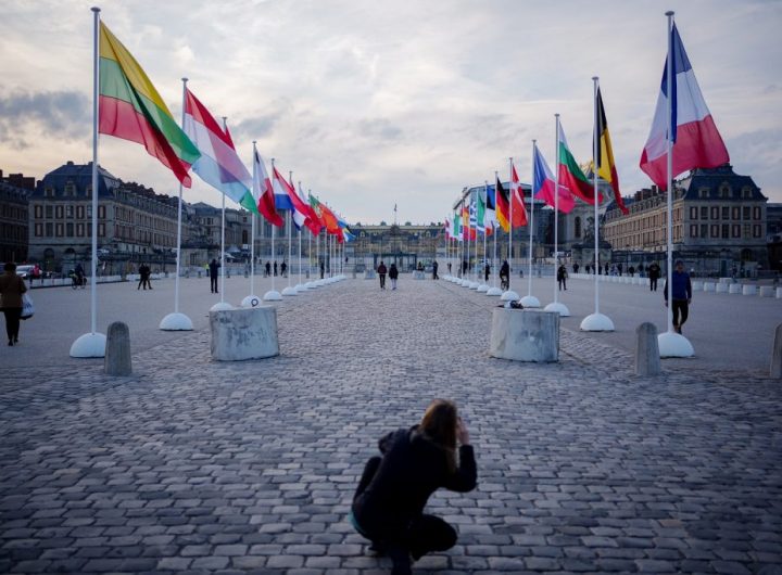 Туристка снима знамената на страните от ЕС, инсталирани пред двореца Версай в Париж. Снимка: publico.es
