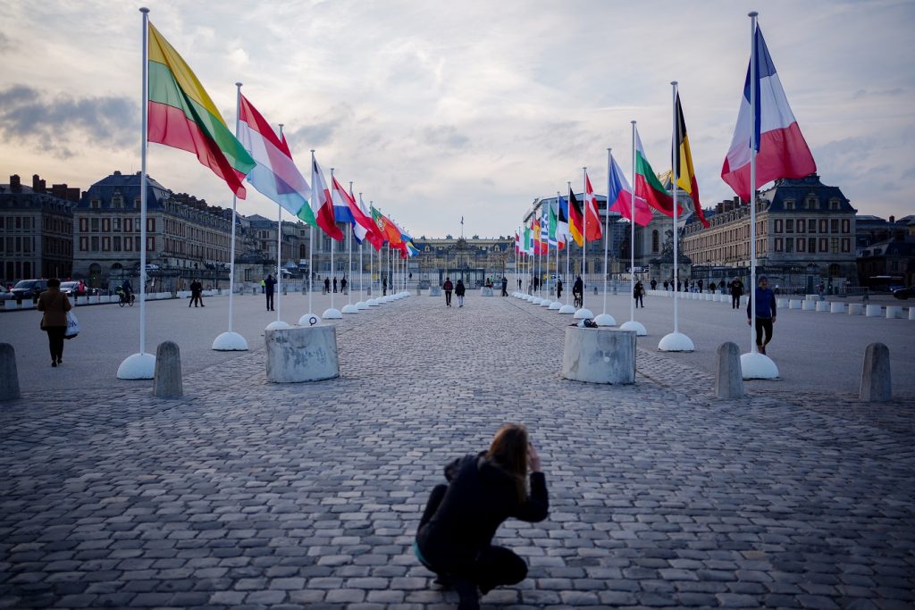 Туристка снима знамената на страните от ЕС, инсталирани пред двореца Версай в Париж. Снимка: publico.es