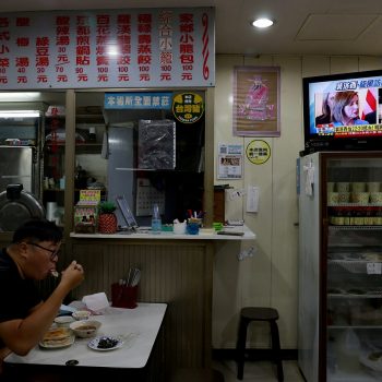 Жител на Тайпе, Тайван, вечеря в заведение, докато по телевизията върви репортаж за посещението на Нанси Пелоси на острова. Снимка: publico.es