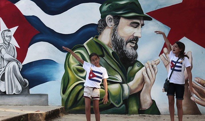 Кубински деца рецитират стихове пред стенопис с образите на Фидел Кастро и поета революционер Хосе Марти. Снимка: resumenlatinoamericano.org