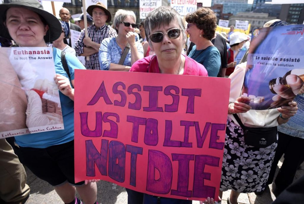 "Помогнете ни да живеем, не да умрем" - пише на плаката на тази канадка, недоволна от "лесната" евтаназия, и трудната помощ за бедните в страната ѝ. Снимка: thestar.com