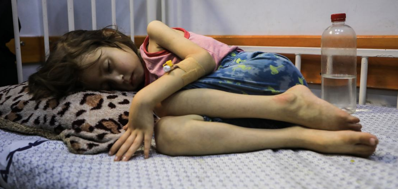Дете, страдащо от недохранване, лежи на легло в болницата „Patient Society Hospital“ в град Газа. УНИЦЕФ/Мохамед Натил
